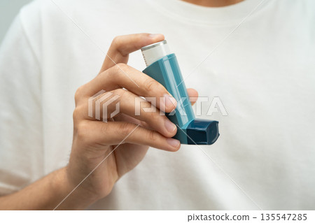 Asthma and chronic obstructive pulmonary disease COPD, Asian young man using metered dose inhaler MDI. Asthma and chronic obstructive pulmonary disease COPD, Asian young man using metered dose inhaler MDI. 135547285