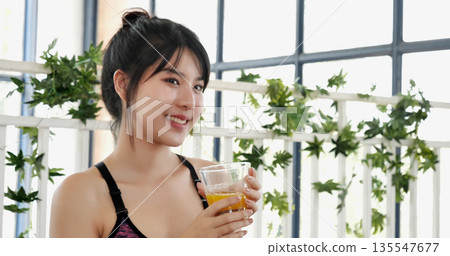 Asian women smile laugh look at camera health care home fitness lifestyle. Women hands holding cold orange juice fresh fruit cool drinking. Beautiful female pouring orange juice from cocktail bottle 135547677