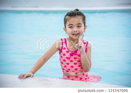 Portrait Girl in pink swimsuit playful in swimming pool summer time with pink swimwear, blue water at hotel swimming pool outdoor. Toddler girl Kid smile laugh look at camera. Happy girl swim playful Portrait Girl in pink swimsuit playful in swimming pool summer time with pink swimwear, blue water at hotel swimming pool outdoor. Toddler girl Kid smile laugh look at camera. Happy girl swim playful 135547806