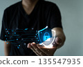 Hand holding glowing digital shield with lock and data lines, symbolizing cybersecurity 135547935