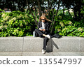 Relaxed successful businesswoman sitting in park on lunch break and enjoying scrolling smartphone. 135547997