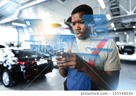 Young man checks data on phone in car service shop with digital display 135548030