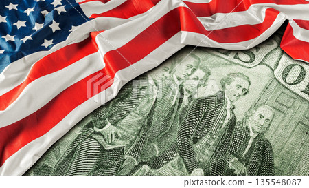 United States flag folds over a one hundred dollar bill on a table 135548087