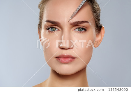 Woman receiving treatment with needle on forehead in a clinic during daylight Woman receiving treatment with needle on forehead in a clinic during daylight 135548090
