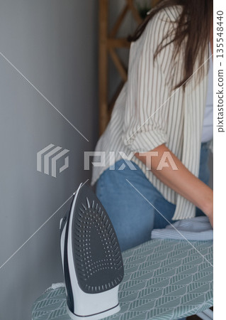 Steam treatment of clothes to kill bacteria woman in casual clothes ironing garments caring for family health Steam treatment of clothes to kill bacteria woman in casual clothes ironing garments caring for family health 135548440