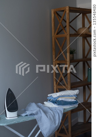 Neatly placed iron on ironing board showing order and efficient organization of daily home routine Neatly placed iron on ironing board showing order and efficient organization of daily home routine 135548480