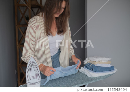 Hot steam ironing for perfect clothes woman caring for fabric quality and keeping wardrobe neat and organized Hot steam ironing for perfect clothes woman caring for fabric quality and keeping wardrobe neat and organized 135548494