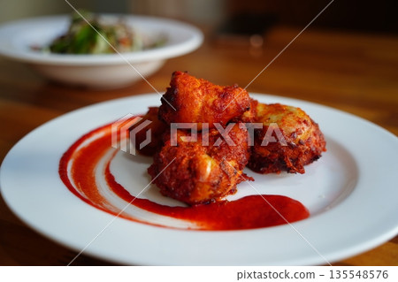 Spicy Fried Chicken Bites with Red Chili Sauce on a White Plate Spicy Fried Chicken Bites with Red Chili Sauce on a White Plate 135548576