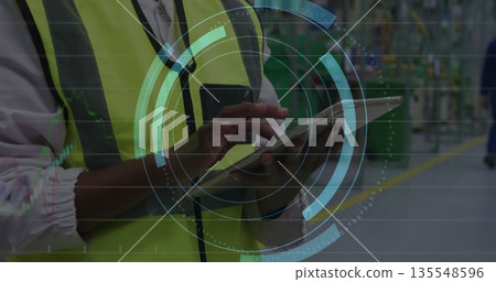 Monitoring production line technician wearing neon safety vest with radio using tablet, copy space 135548596