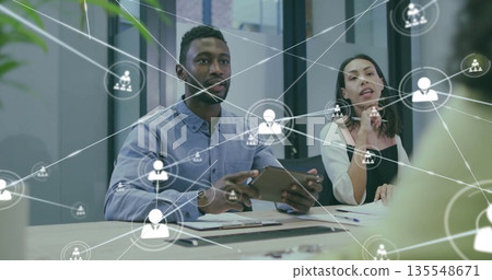 Discussing colleagues with tablet, papers and notepad in conference room with digital network icons Discussing colleagues with tablet, papers and notepad in conference room with digital network icons 135548671