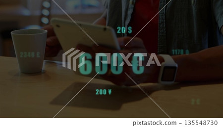 Holding tablet, man viewing floating currency graphics beside white mug and smartwatch at cafe 135548730