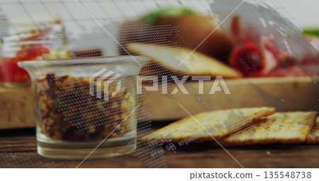 Showing glass jar holding brown spread on wooden kitchen tabletop with crackers and red bell pepper 135548738
