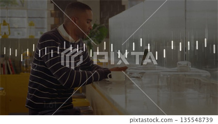 Man wearing striped sweater working on laptop at coffee shop counter, with cup and glass canisters Man wearing striped sweater working on laptop at coffee shop counter, with cup and glass canisters 135548739
