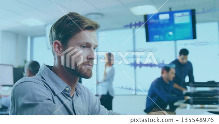 Focusing bearded man in button-down shirt typing on computer in open-plan office with data display Focusing bearded man in button-down shirt typing on computer in open-plan office with data display 135548976
