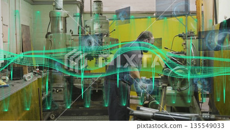 Operating technician adjusting milling machine in machine shop with digital overlays, copy space Operating technician adjusting milling machine in machine shop with digital overlays, copy space 135549033