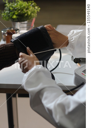 A doctor's hands carefully taking a patient's blood pressure using a sphygmomanometer. A doctor's hands carefully taking a patient's blood pressure using a sphygmomanometer. 135549140