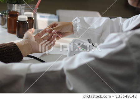 A doctor's hands carefully taking a patient's blood pressure using a sphygmomanometer. 135549148