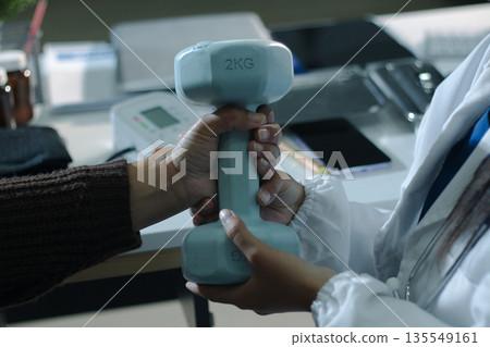 doctor is checking for muscle injuries and using dumbbells test injury and also help with physical therapy strengthen muscles because physical therapy will help strengthen muscles and help blood flow 135549161