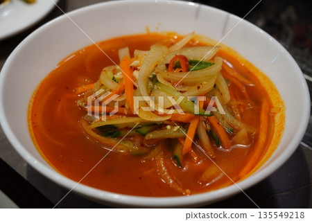 Spicy hot noodle soup, corn noodles served in a white bowl, popular side dish at Korean lamb skewer restaurant. 135549218