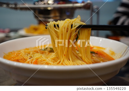 Spicy hot noodle soup, corn noodles served in a white bowl, popular side dish at Korean lamb skewer restaurant. 135549220