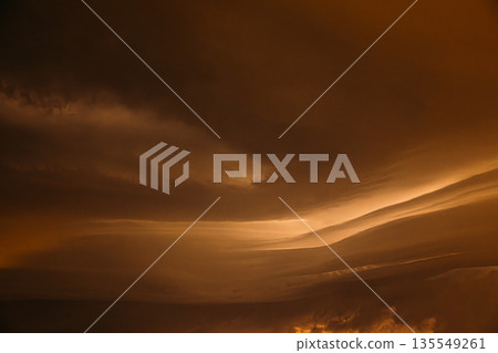 Orange yellow Cloudy Sky With Dark Storm Clouds During Rain. Natural Background With Rainclouds. natural weather background dark yellow backdrop thunderstorm stormy sky 135549261