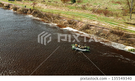 Men Dressed As US American Soldiers Of USA Infantry Of World War II carry out rafting on rubber boats In spring Autumn Day. Group of Soldiers people are preparing to disembark. Aerial view elevated Men Dressed As US American Soldiers Of USA Infantry Of World War II carry out rafting on rubber boats In spring Autumn Day. Group of Soldiers people are preparing to disembark. Aerial view elevated 135549340