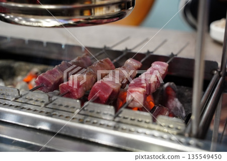 Raw, uncooked lamb skewers on a grill, a popular Chinese barbecue street food, ready for cooking. Raw, uncooked lamb skewers on a grill, a popular Chinese barbecue street food, ready for cooking. 135549450
