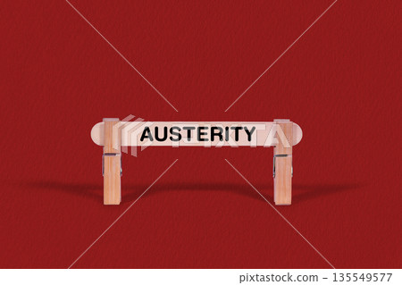 Austerity symbol. Wooden stick braced by Clothespins, beautiful Red Background. Business and Austerity concept with copy space 135549577