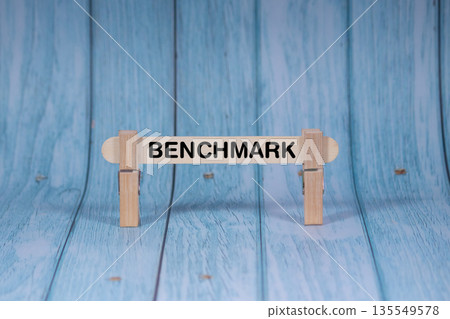 Benchmark symbol. Wooden stick clamped by Clothespins, vivid blue wooden backdrop. Business and Benchmark concept with copy space Benchmark symbol. Wooden stick clamped by Clothespins, vivid blue wooden backdrop. Business and Benchmark concept with copy space 135549578