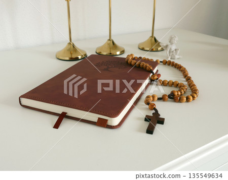 Catholic corner at home. Wooden rosary beads, cross, and prayer book. Faith, symbols, and traditions. 135549634