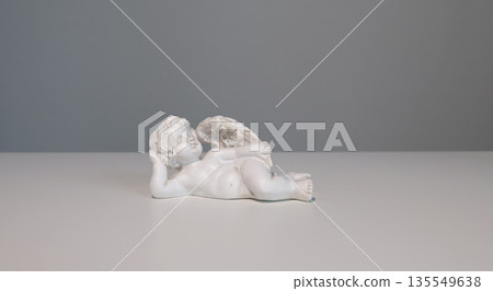 White ceramic angel figurine on white background for design. Faith, symbols, and traditions. White ceramic angel figurine on white background for design. Faith, symbols, and traditions. 135549638