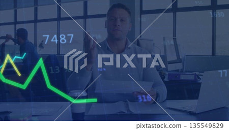 Reading business professional gesturing at holographic finance chart above office desk, with laptop 135549829