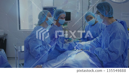 Surgical team performing surgery in operating room, with sterile blue gowns, masks and scalpels Surgical team performing surgery in operating room, with sterile blue gowns, masks and scalpels 135549888