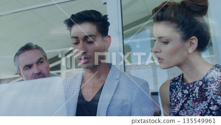 Reviewing mid Indian man wearing blazer analyzing white dotted overlay behind glass wall in office 135549961