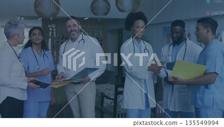 Discussing medical professionals reviewing patient charts in hospital lounge, with stethoscopes Discussing medical professionals reviewing patient charts in hospital lounge, with stethoscopes 135549994