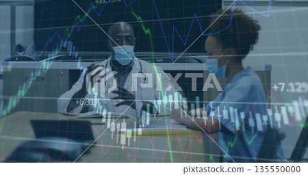 Doctor with stethoscope and mask discussing graphs while nurse types on tablet in conference room 135550000
