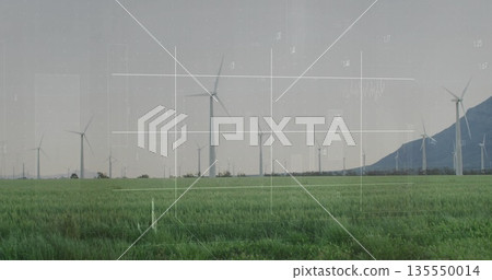 Towering central wind turbine rising above green crop field, with distant mountain ridge 135550014