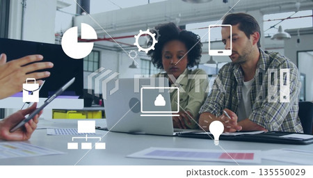 Collaborating professionals reviewing laptop screens in open workspace, with tablet and data icons 135550029