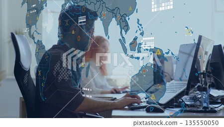 Monitoring two IT analysts in shirts scanning alerts in office, with monitors world map overlay 135550050
