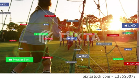 Goalkeeper stopping ball at goal net on soccer pitch at sunset, with floating notification icons Goalkeeper stopping ball at goal net on soccer pitch at sunset, with floating notification icons 135550072