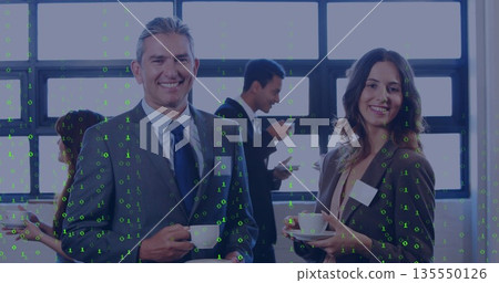 Smiling businessman and colleague holding coffee cups in conference break area, with coffee carafe 135550126