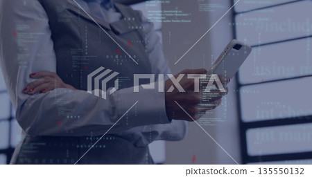 Holding smartphone professional woman in vest and shirt viewing code projections at modern office Holding smartphone professional woman in vest and shirt viewing code projections at modern office 135550132