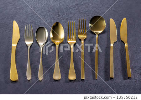 黑色桌子上擺放著金色的刀叉。 135550212