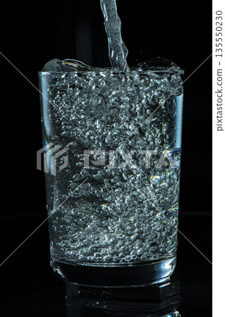 在黑色背景下向玻璃杯中倒水 135550230