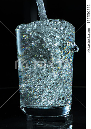 在黑色背景下向玻璃杯中倒水 135550231
