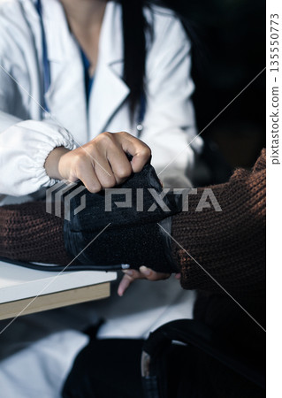 A doctor's hands carefully taking a patient's blood pressure using a sphygmomanometer. 135550773