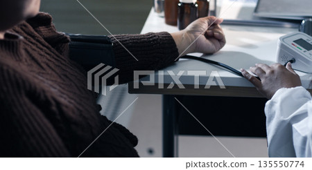 A doctor's hands carefully taking a patient's blood pressure using a sphygmomanometer. A doctor's hands carefully taking a patient's blood pressure using a sphygmomanometer. 135550774