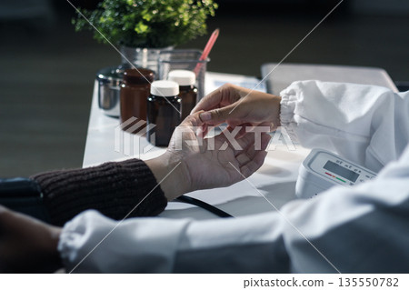 A doctor's hands carefully taking a patient's blood pressure using a sphygmomanometer. A doctor's hands carefully taking a patient's blood pressure using a sphygmomanometer. 135550782