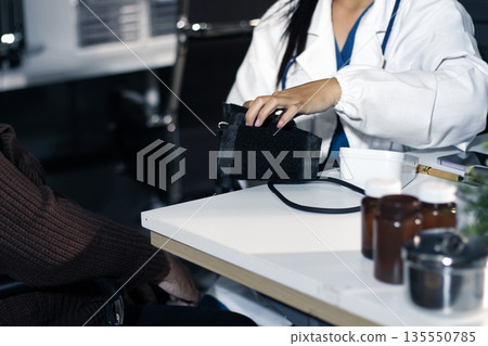 A doctor's hands carefully taking a patient's blood pressure using a sphygmomanometer. A doctor's hands carefully taking a patient's blood pressure using a sphygmomanometer. 135550785