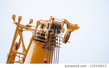 Industrial crane hoist system with steel cables and pulleys. Heavy construction machinery for infrastructure development, engineering precision, safety operations, and modern industrial technology. 135550857